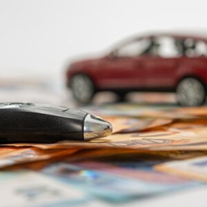 key and red toy car on pile of euro banknotes, buy or sell a car, rent a car or insurance concept